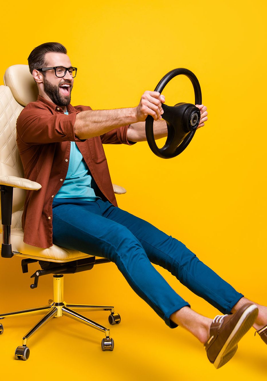 Full length body photo of happy fooling man in chair keeping steering wheel pretending car driver isolated vivid yellow color background.